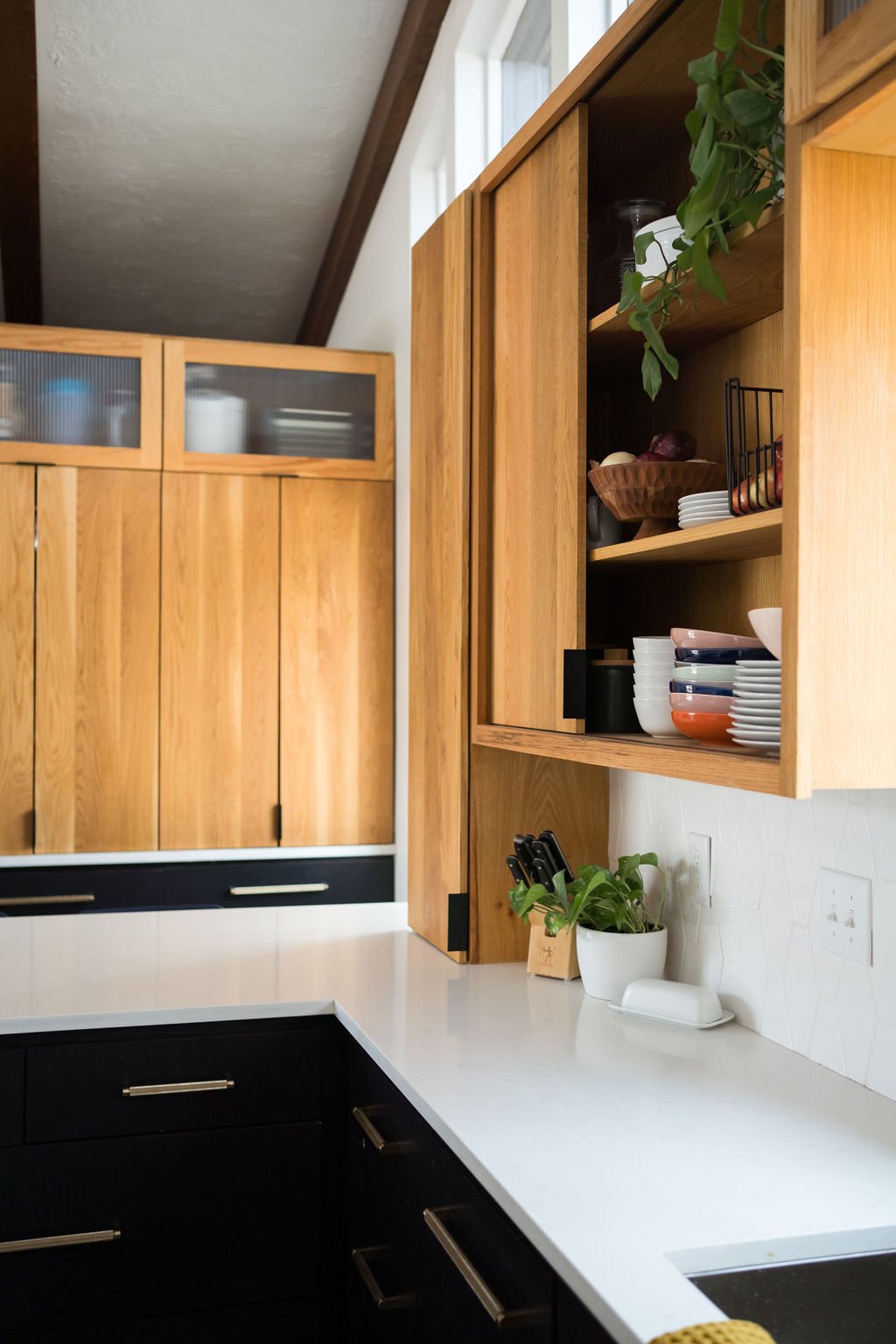 Wood upper cabinets and black lower cabinets with white countertops in a mid-century modern kitchen remodel.