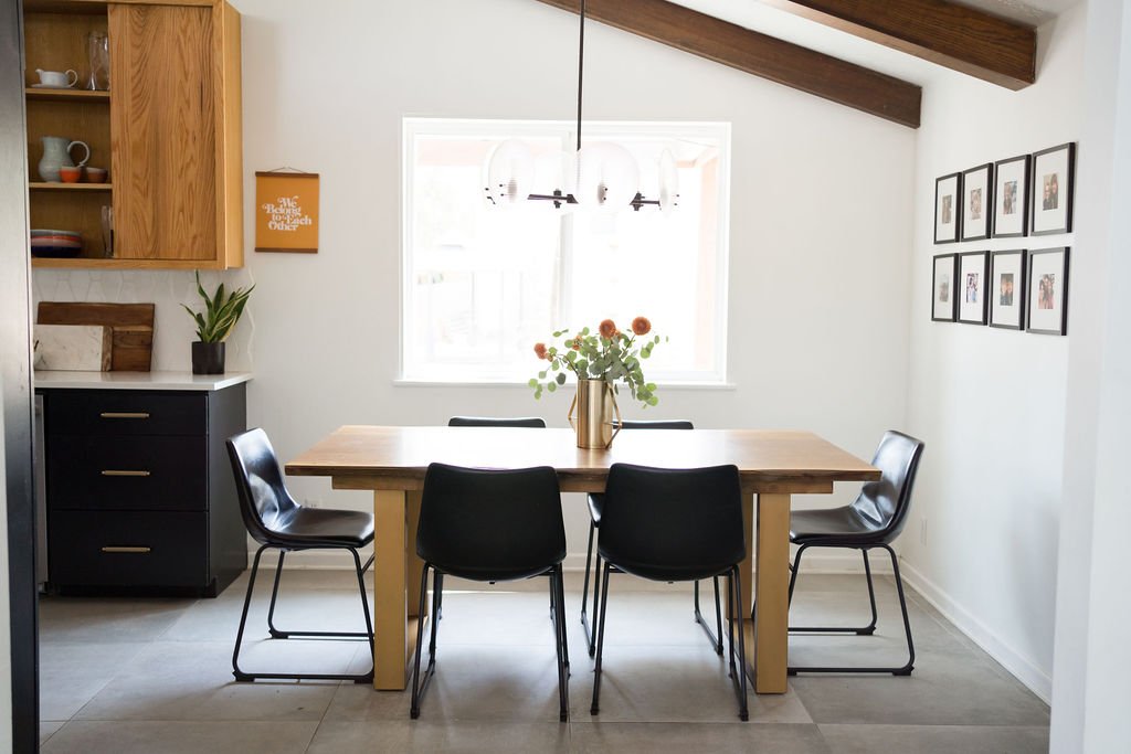 Dining area with wood table and black leather chairs as part of an open concept mid-century modern kitchen remodel.